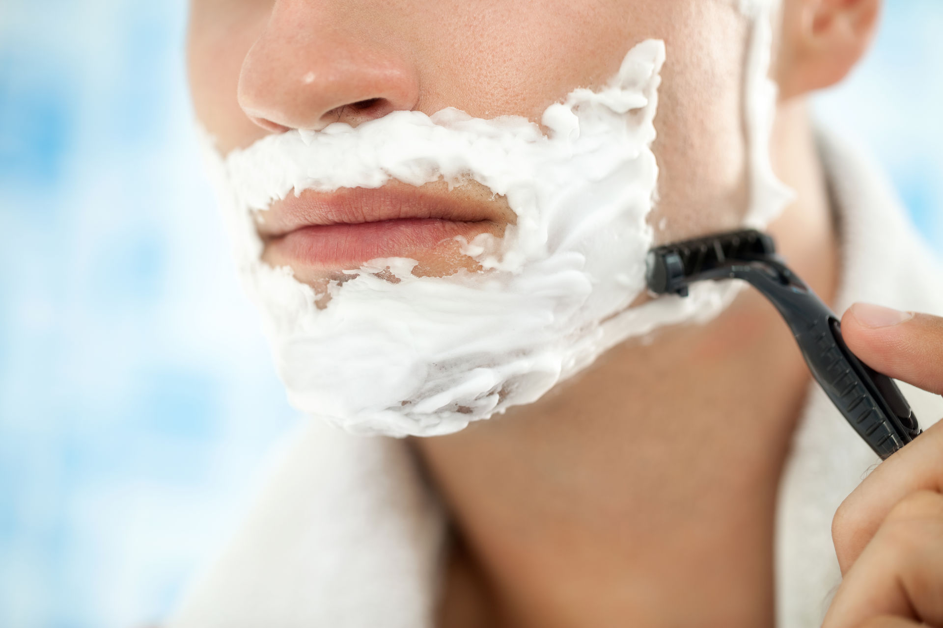 Male shaving facial hair with razor and shaving cream on face Male shaving facial hair with razor and shaving cream on face