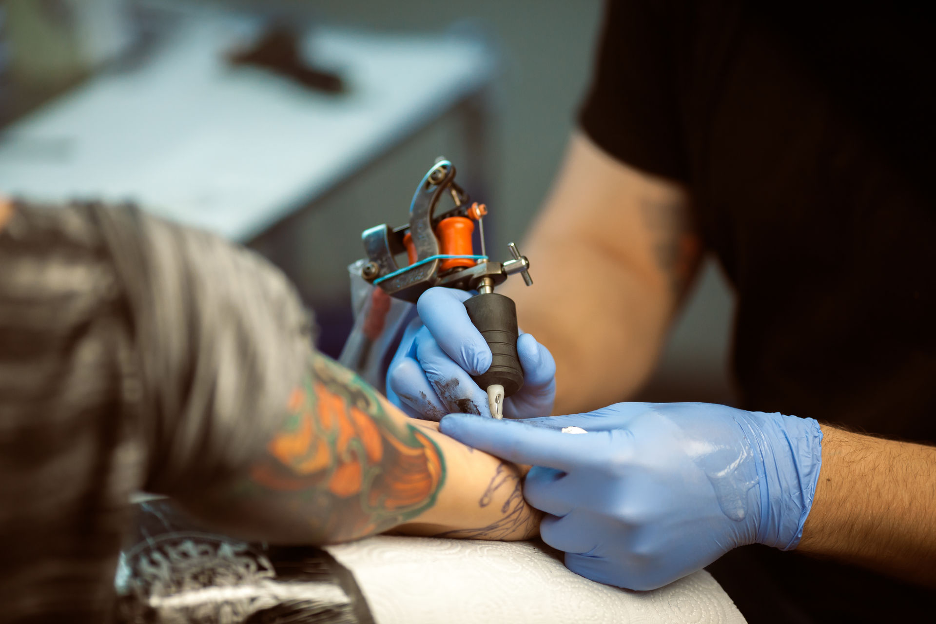 Arm being tattooed by tattoo artist with gloves on Arm being tattooed by tattoo artist with gloves on